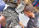 Data collector filling in a survey form with participant who sells charcoal in Dwazack