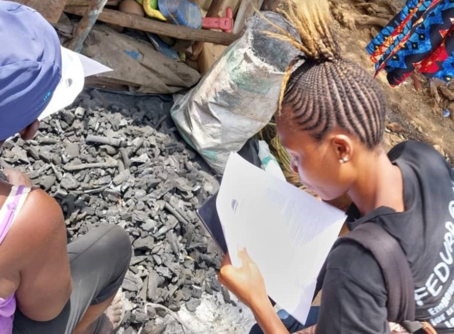 Data collector filling in a survey form with participant who sells charcoal in Dwazack